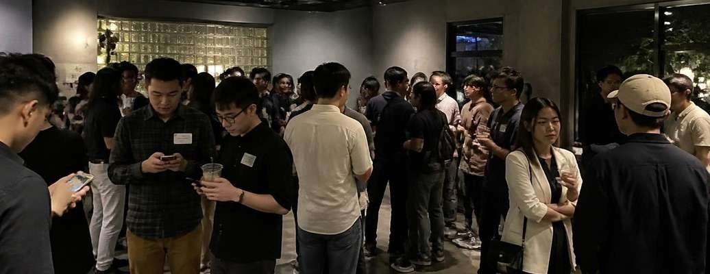A crowded networking event where many guests look at phones